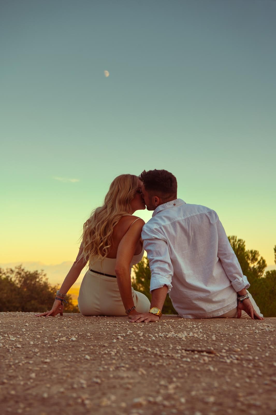 Los novios besándose al atardecer con la luna detrás